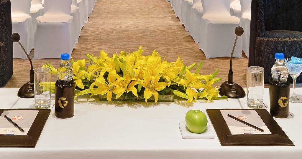 班加罗尔欢迎酒店 外观 照片 A table with a microphone, a bottle of water, a green apple and a flower arrangement